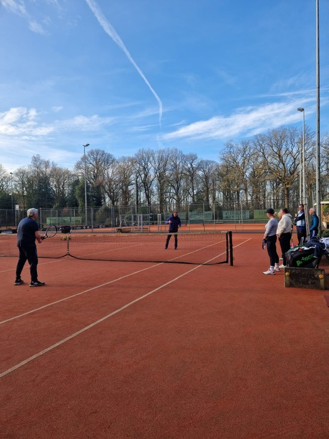 Tennissers samen op de baan tijdens een groepsmoment